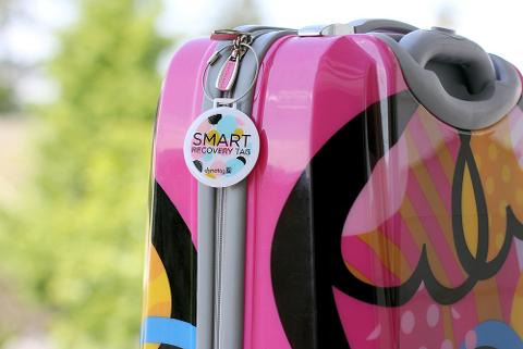 A Dynotag smart recovery tag clipped to a suitcase